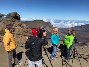 A cameraman focuses on host and scientist overlooking Hawaiian landscape