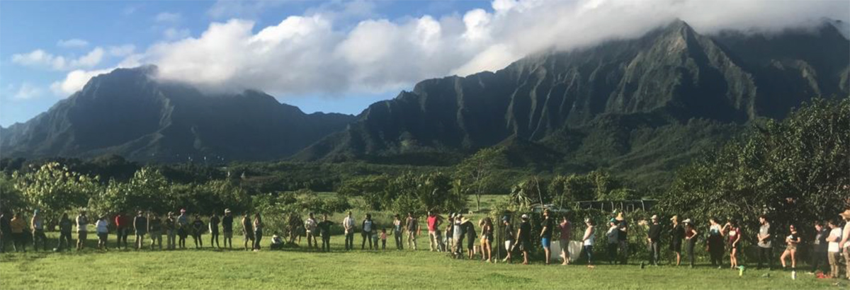 People arranged in a circle with background of mountains of the Pali