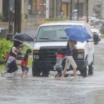 A family wades across a flooded road in Tumon, Guam