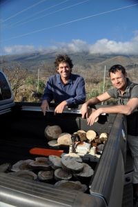 Patrick Hart poses with a collaborator next to a truck with cut slices of tree trunks.