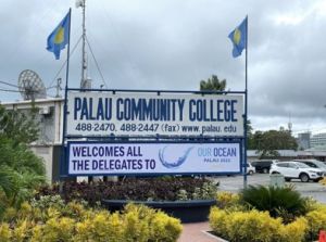 Photo with Palau Community College sign and welcome to all Our Ocean delegates message.