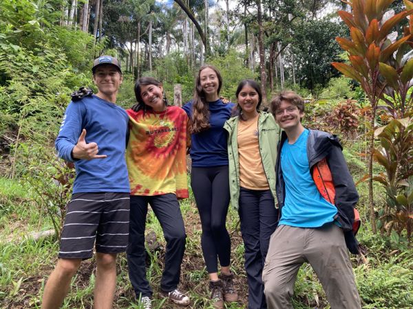 Five students pose against work area