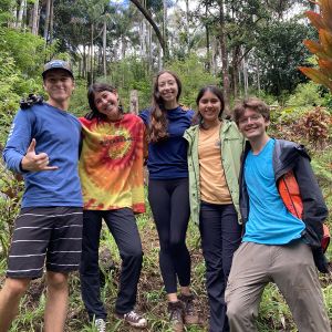 Five SURF students pose in front of a steep vegetated slope