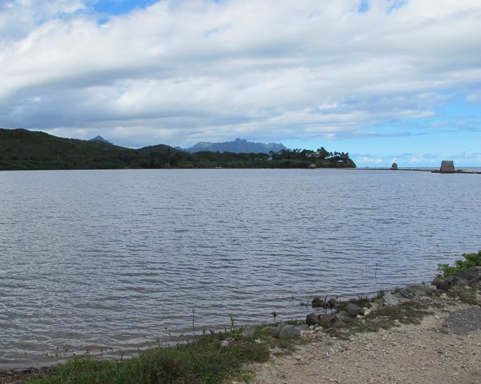 Looking across the waters of a large, enclosed fishpond across to higher terrain in the distance