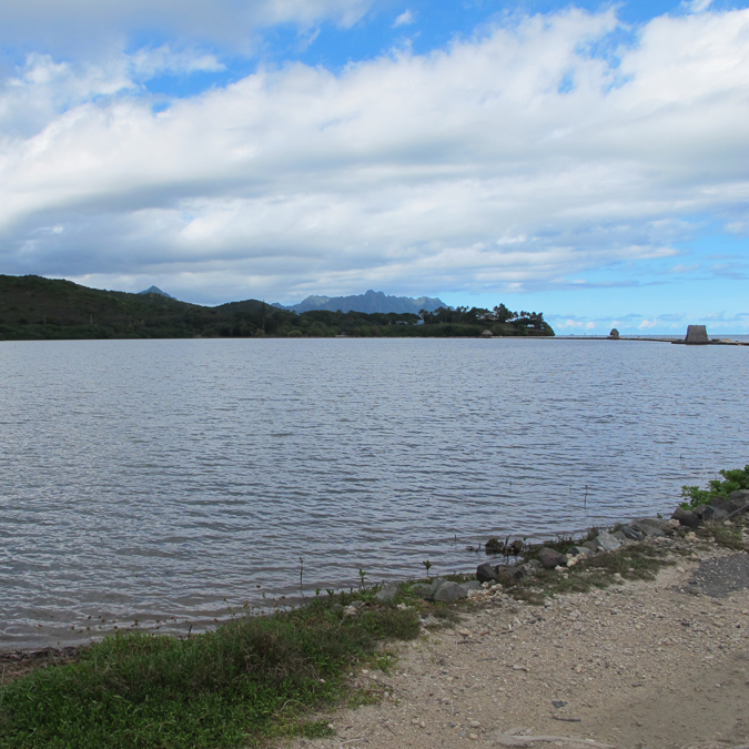 Looking across the waters of a large, enclosed fishpond across to higher terrain in the distance