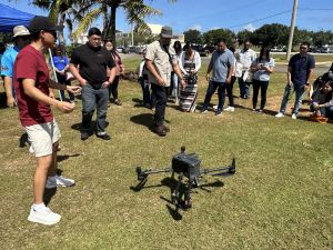 People are standing around an unmanned aerial vehicle, or drone, outside on a grassy area.
