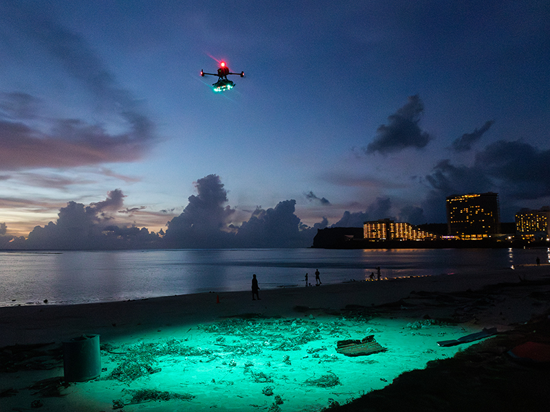 Dusk enhances the colorful spotlight on the sand sent down from a hovering drone