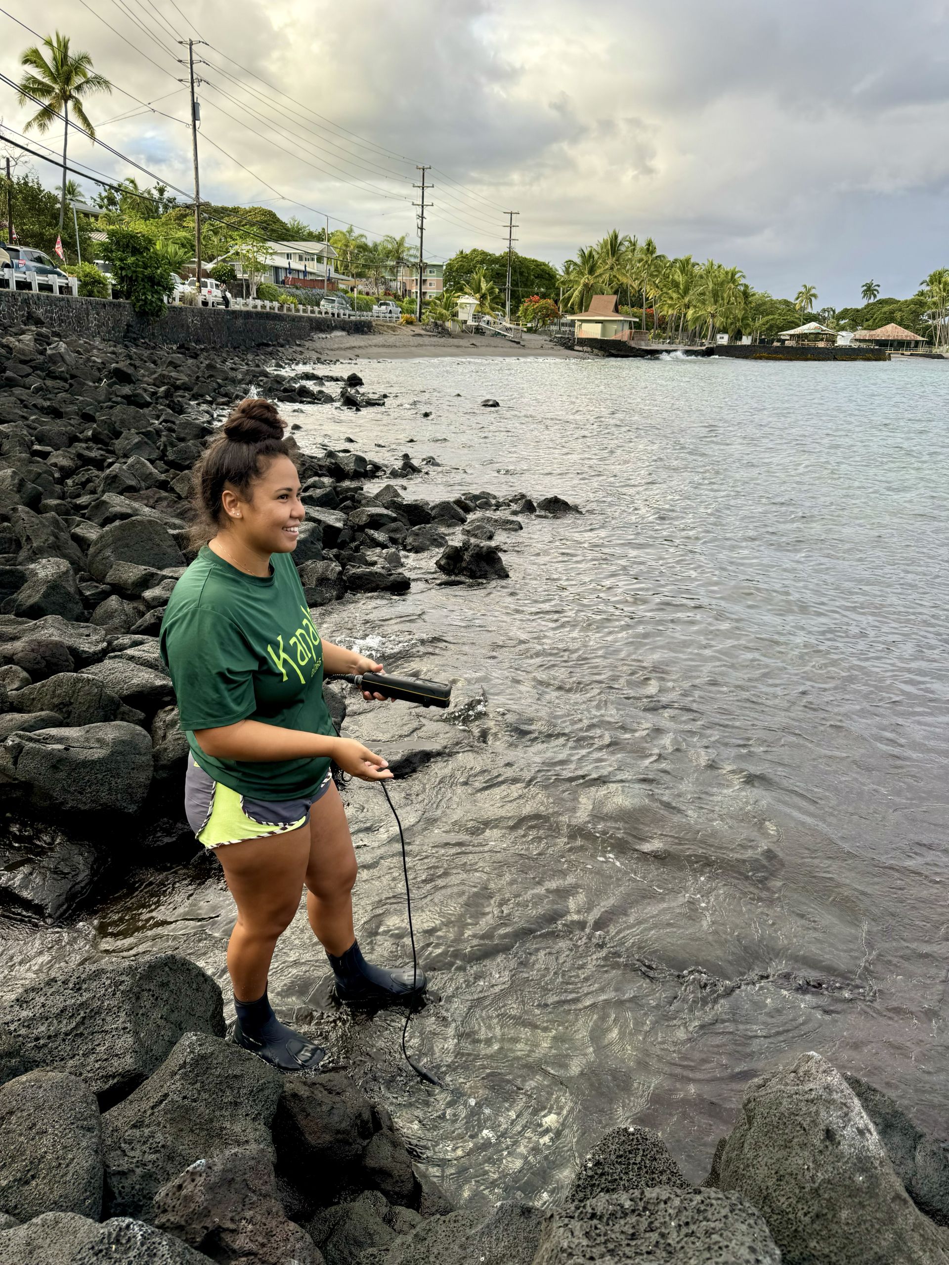 Ihilani standing on rocks next to the ocean.