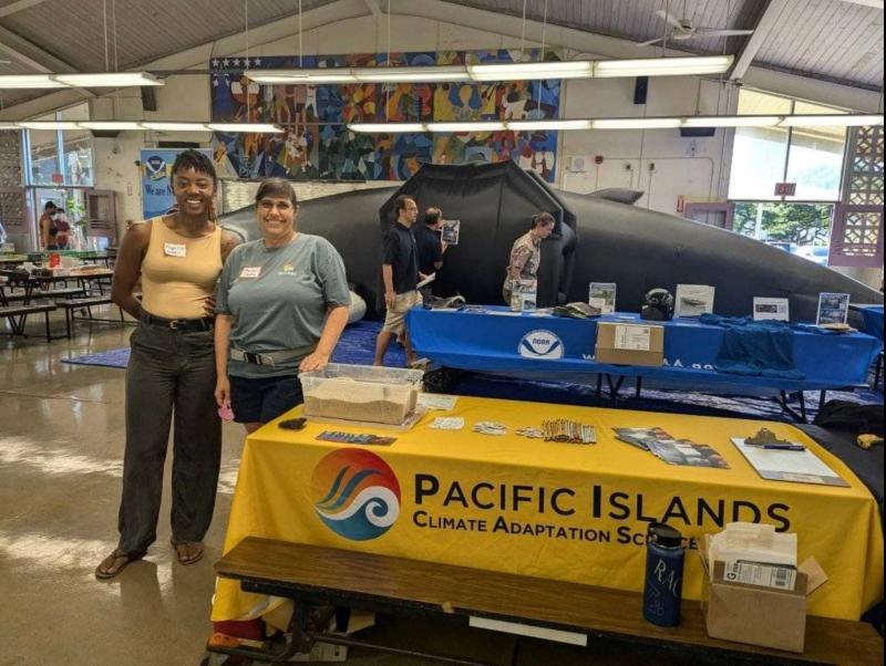 Green and Lentz stand in front of the PI-CASC expo table at the conference.