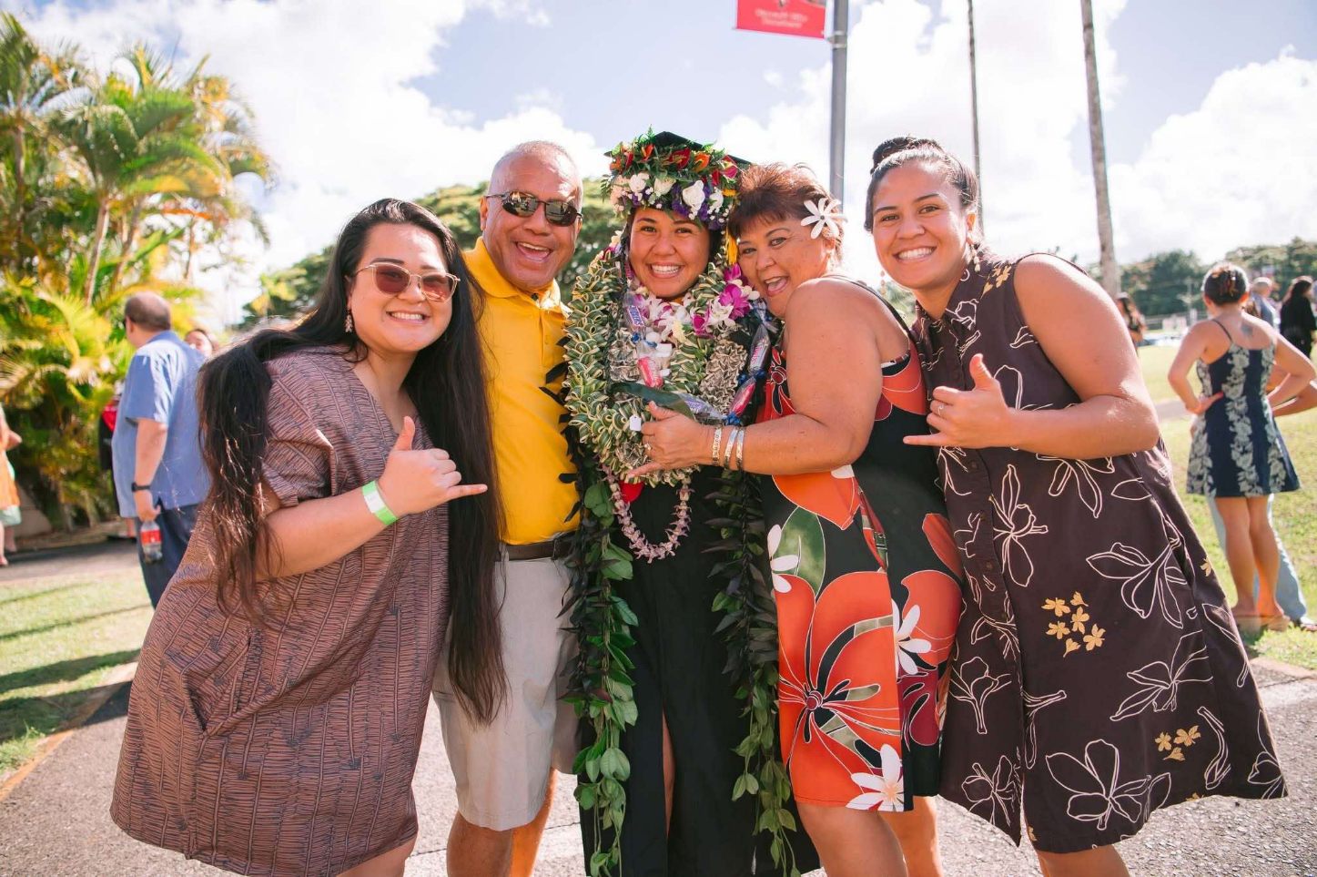 Ihilani stands with her cap and gown, adorned with lei, with her familiy.