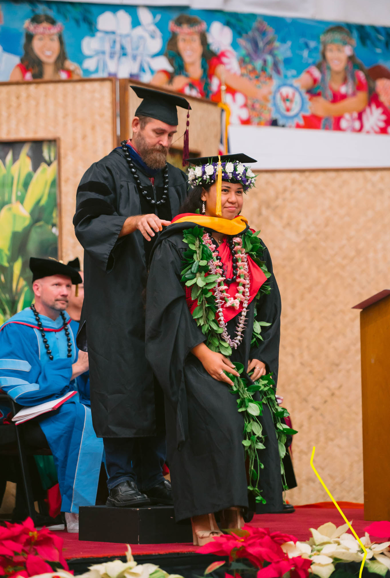 Ihilani on stage at graduation withh hood and lei.