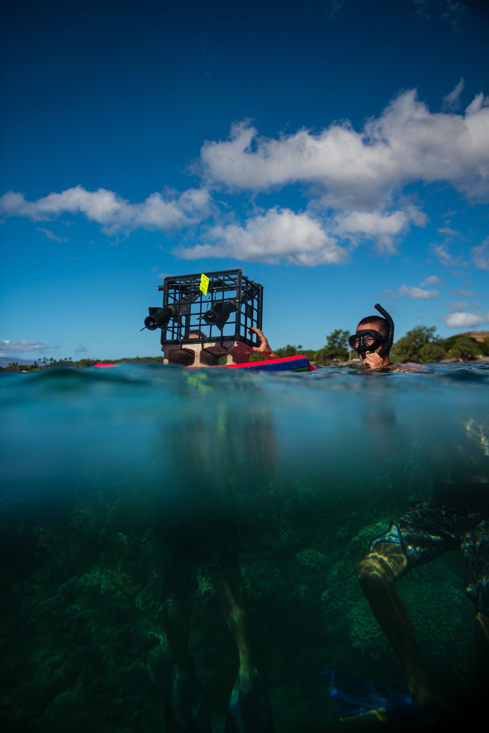 Sean wades in the ocean holding on the floating equiptment.