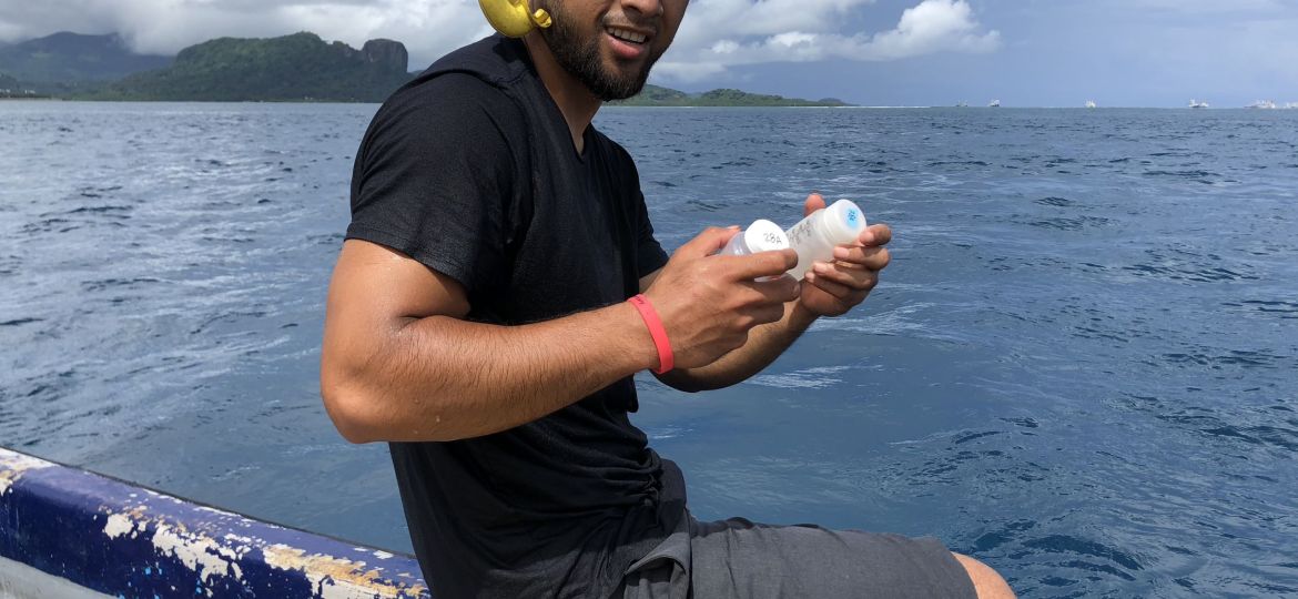 Bryan wearing snorkel on head, sitting off the side of a boat, holding samples.